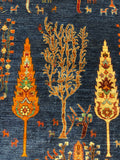 Close-up of a woven rug or textile with a dark navy blue ground and large ornate botanical motifs in orange, beige, and small green accents.