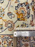 Close-up of a patterned area rug with a stainless steel ruler placed vertically to show the scale of the weave and fringed edge.